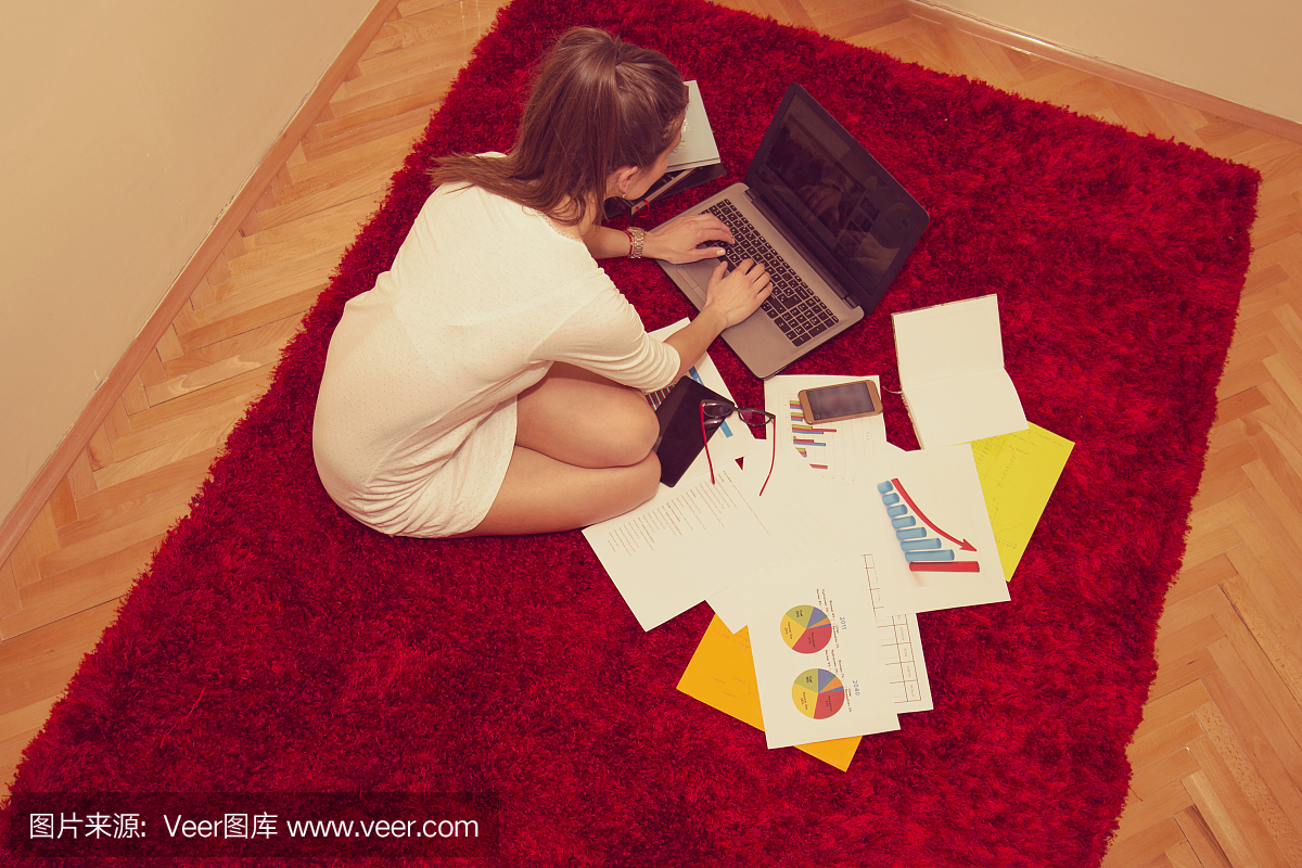 女人坐在地板上,在笔记本电脑上工作