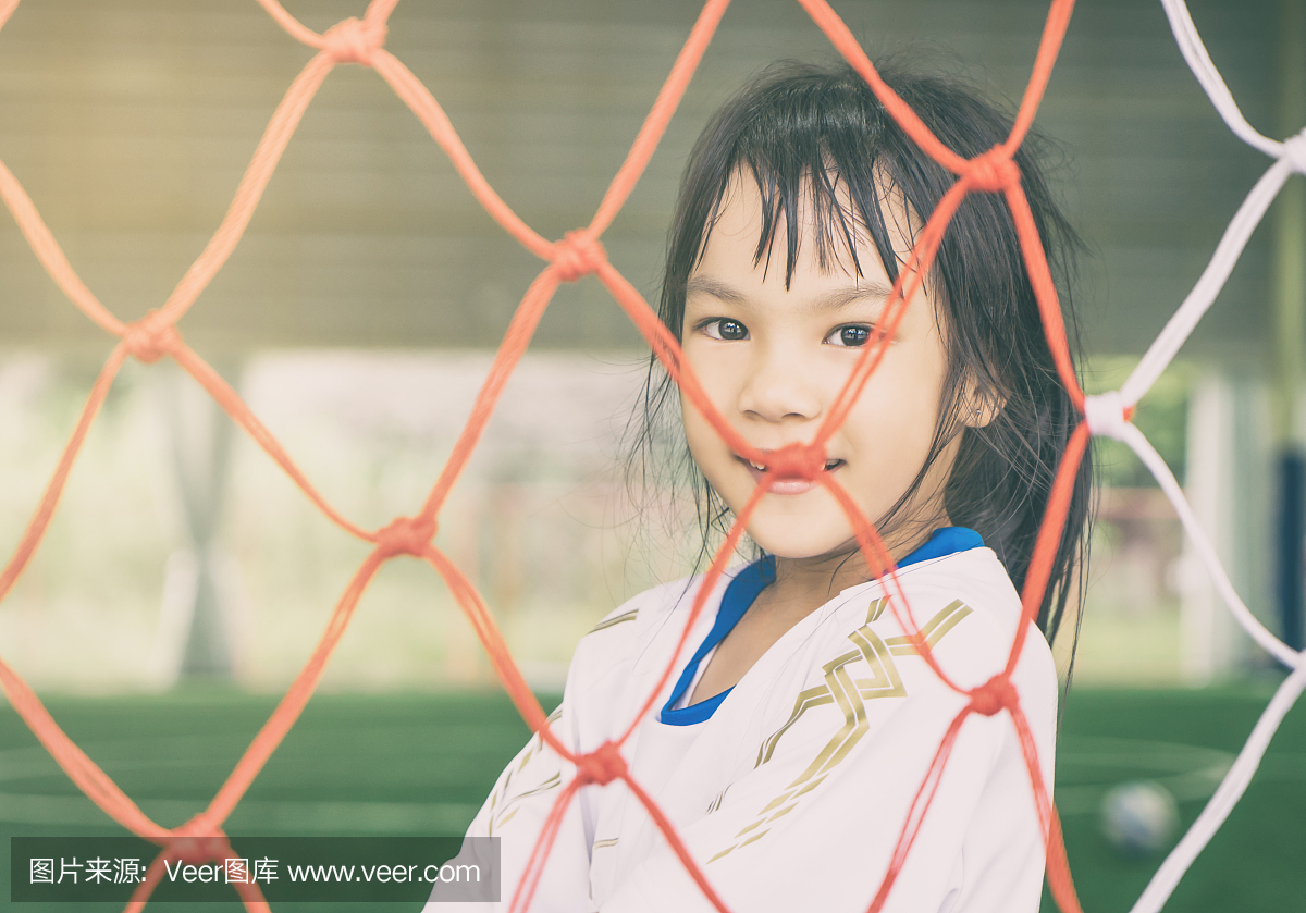 在足球足球目标网后面的快乐女孩儿童体育概念