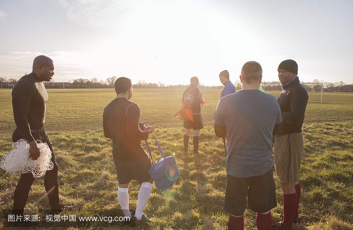 成熟的男性足球运动员在场上结合