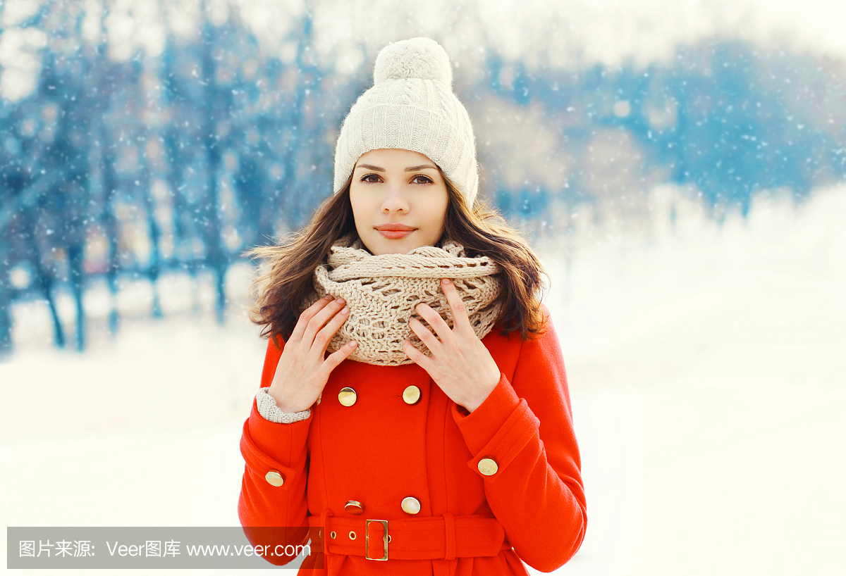 穿着红色外套,帽子和围巾冬天的美丽的年轻女