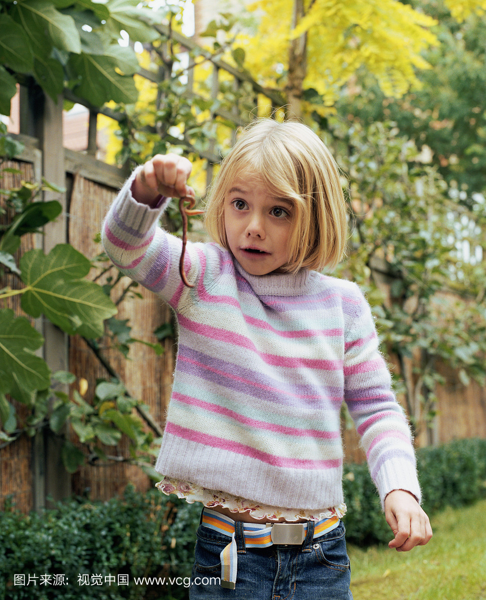 女孩(5-7)在花园里抱着蠕虫,拉面部表情