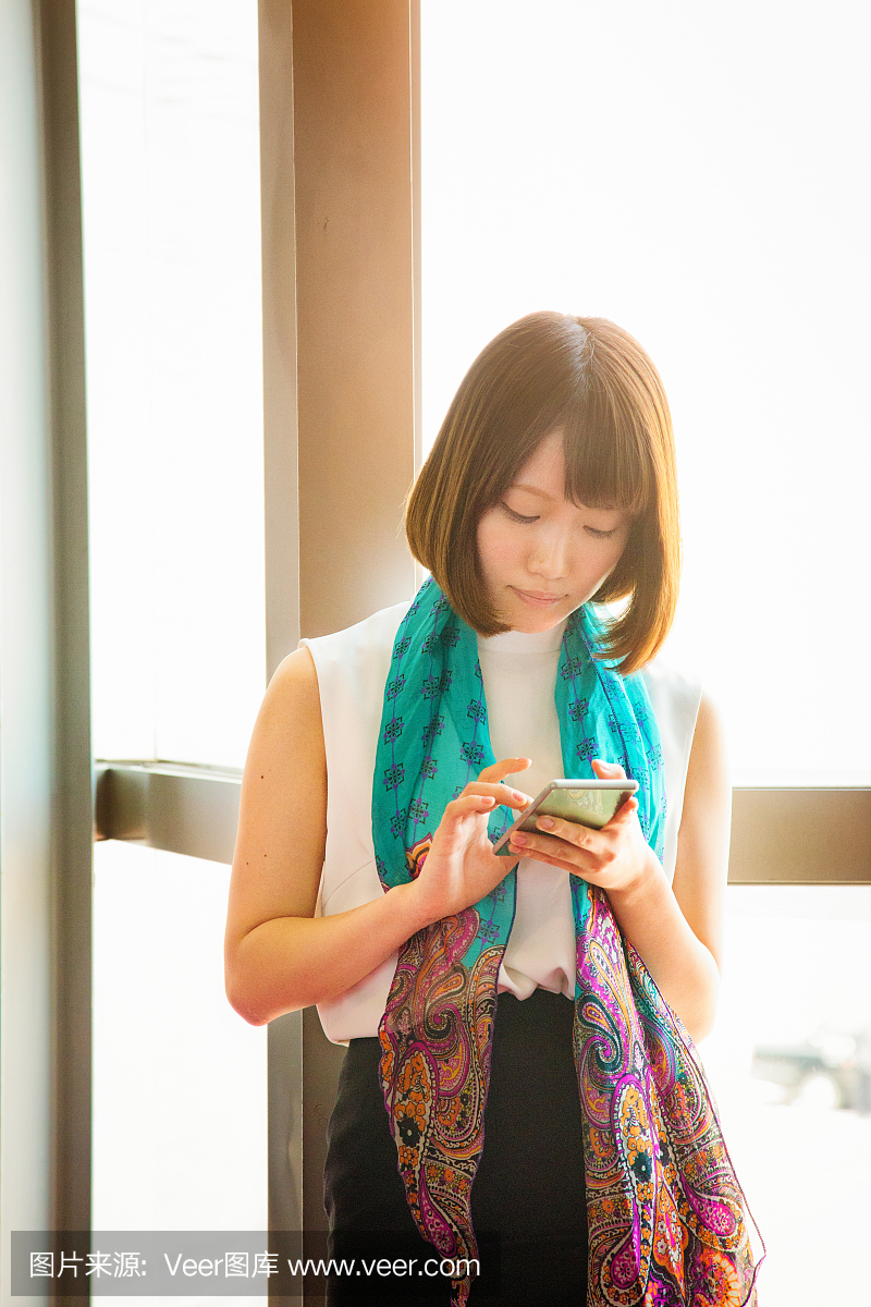 年轻的害羞的日本女用她的手机