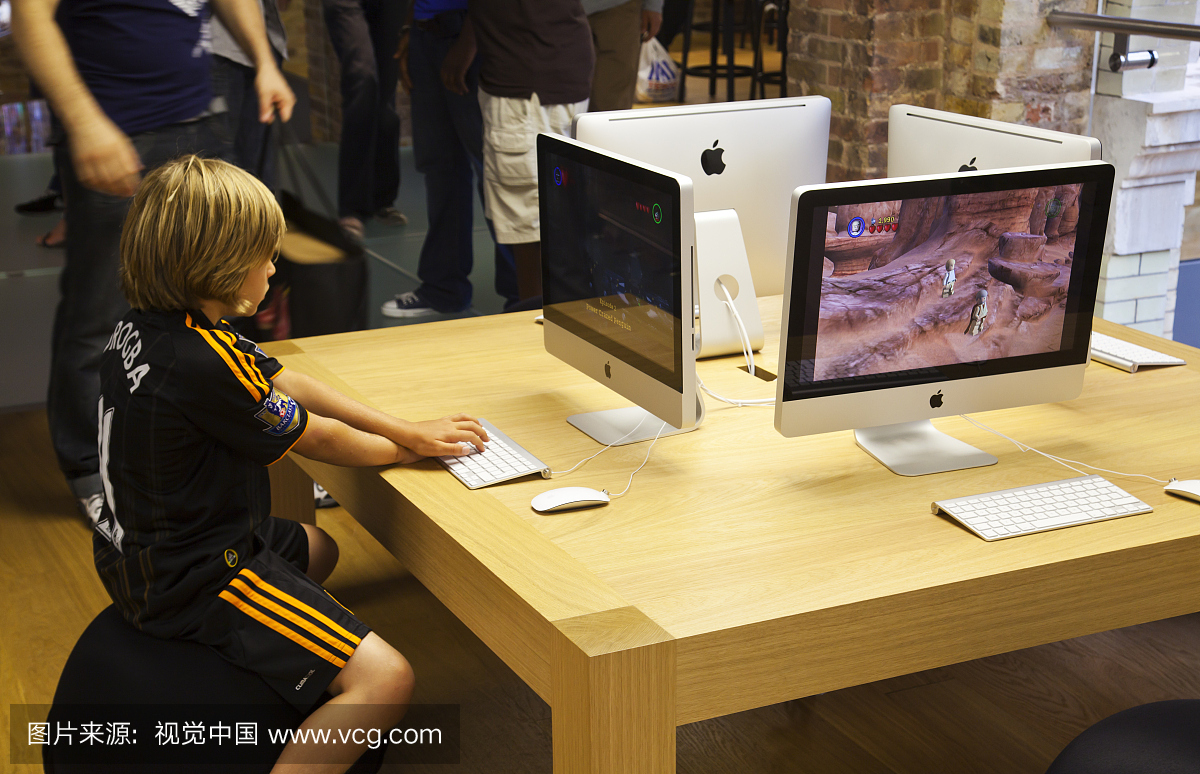 集中儿童玩电脑游戏在新的iMac在Mac中心苹果