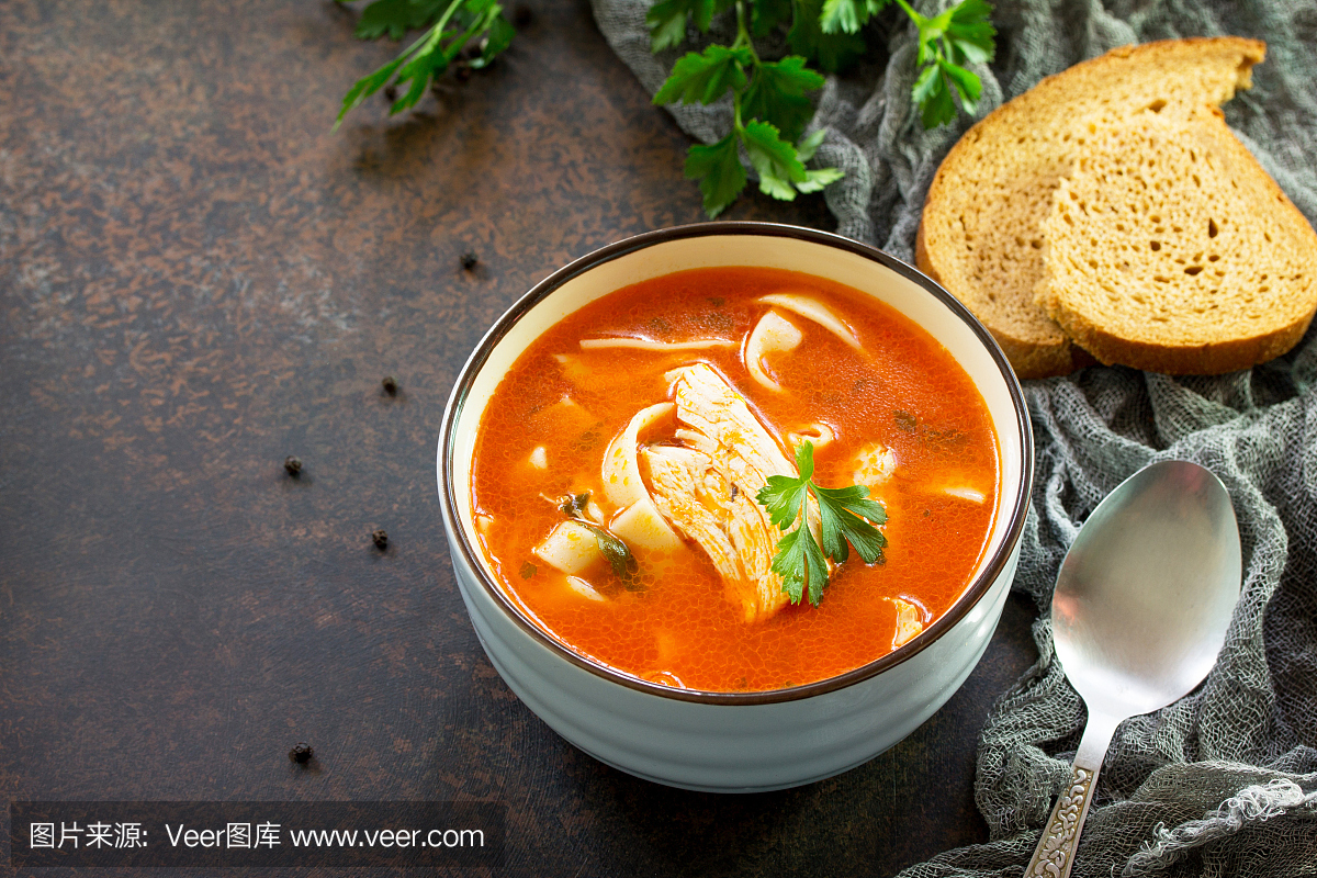 番茄汤配意大利面和鸡在深色石背景上的碗里。