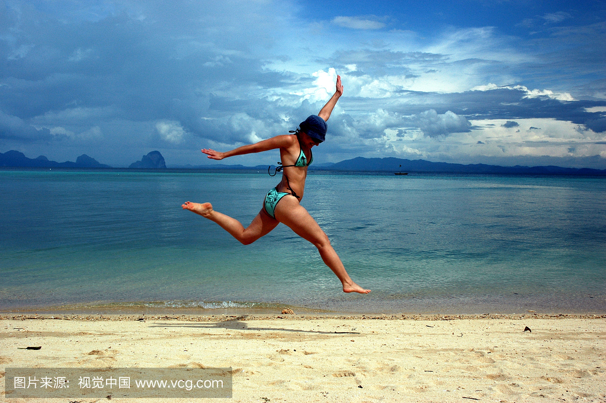 比基尼女孩在泰国岛海滩跳空中