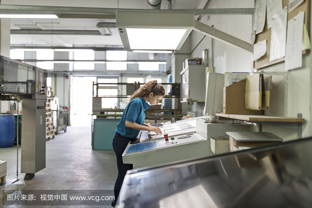 女性工作者在纸上的测量图在印刷厂