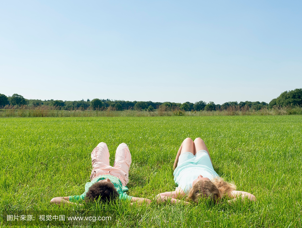 女孩和男孩躺在田野的后视图