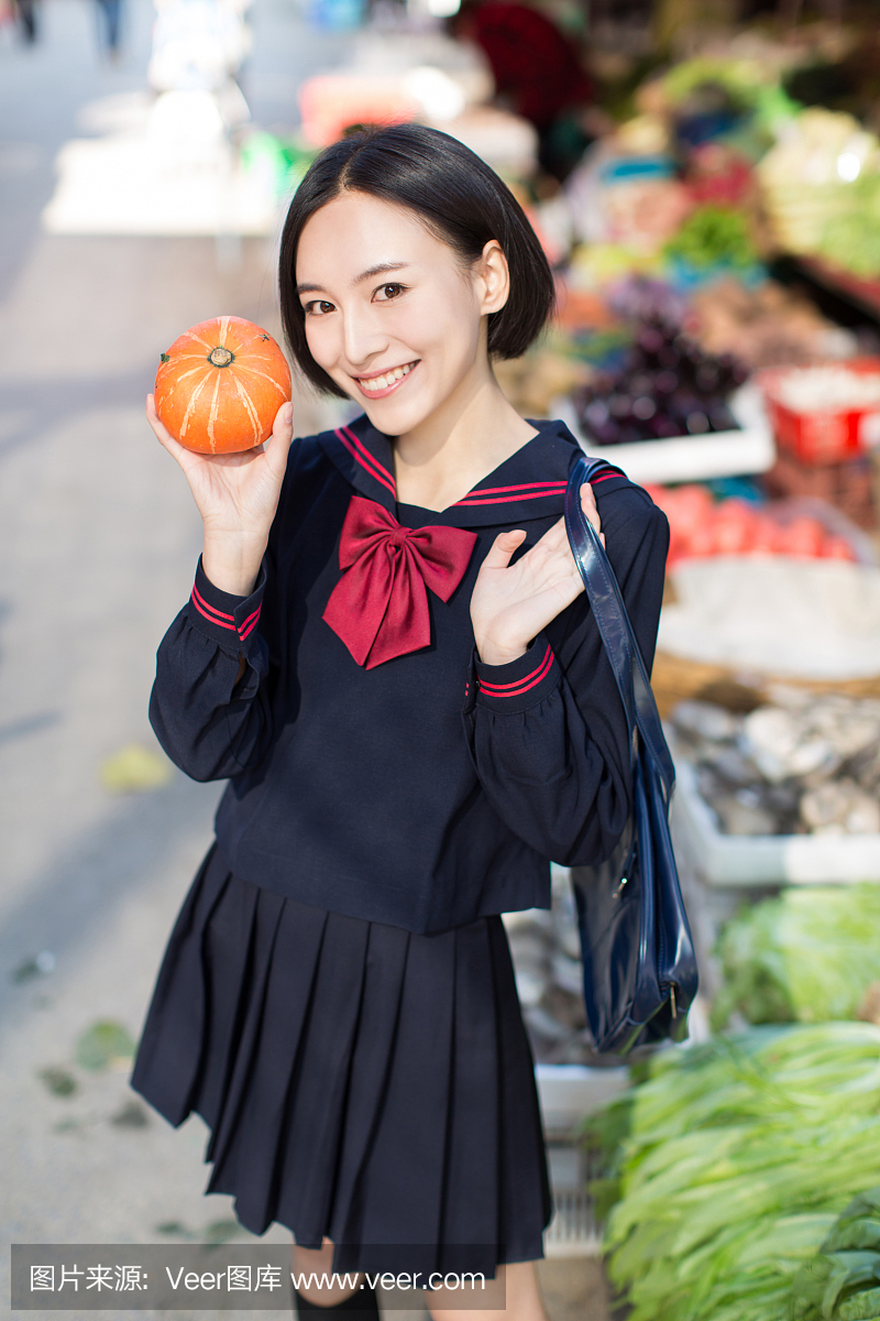 美丽的中国女学生在市场上买水果和蔬菜