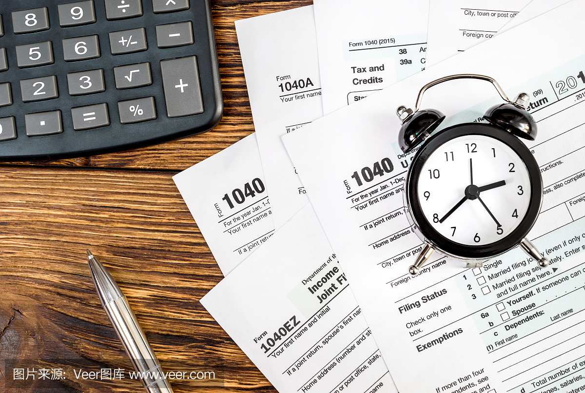 与时钟,笔和计算器在办公室的木桌上的税务表