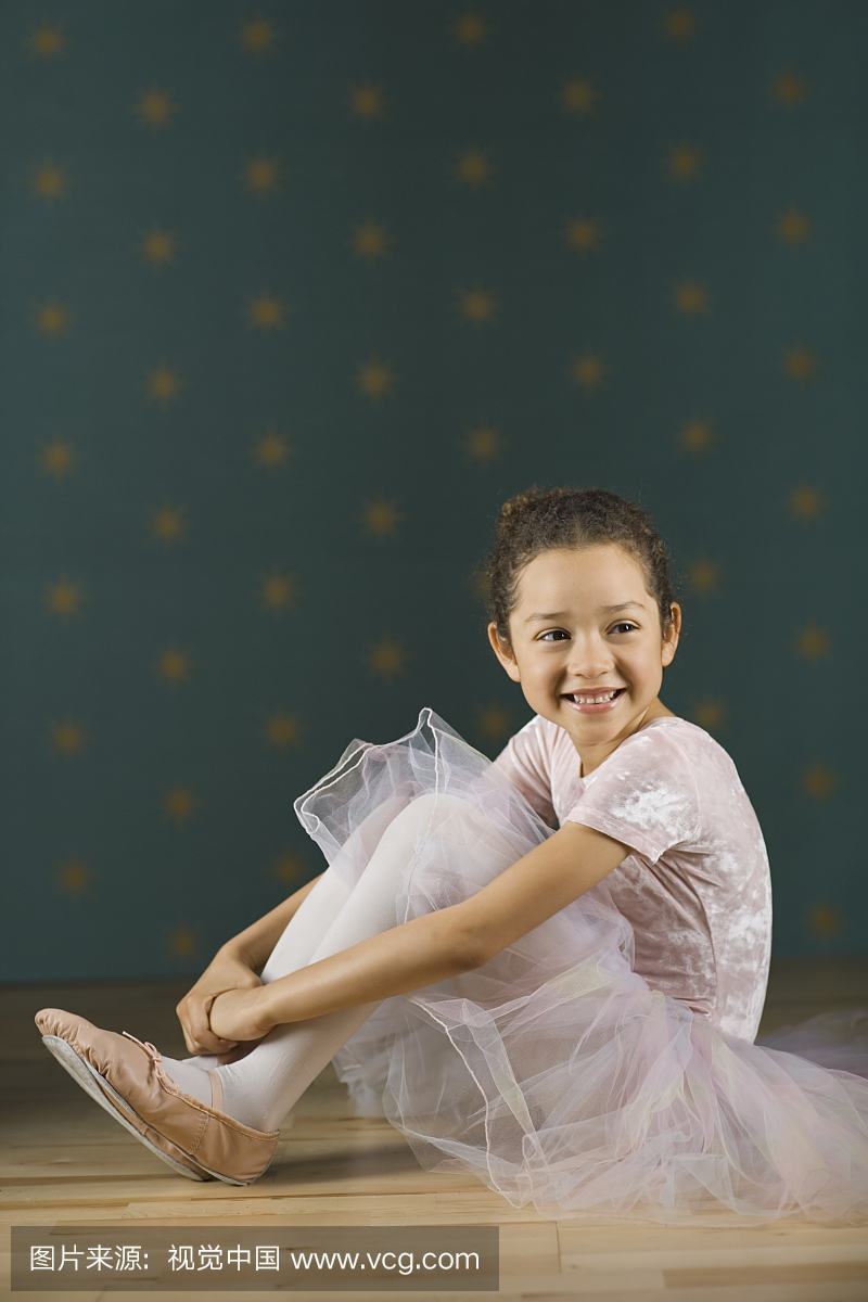 女孩(5-7)在芭蕾舞服装坐在地板上