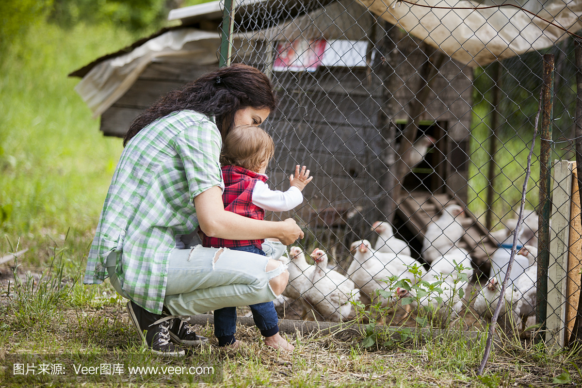 母亲和女儿在养鸡场玩得开心