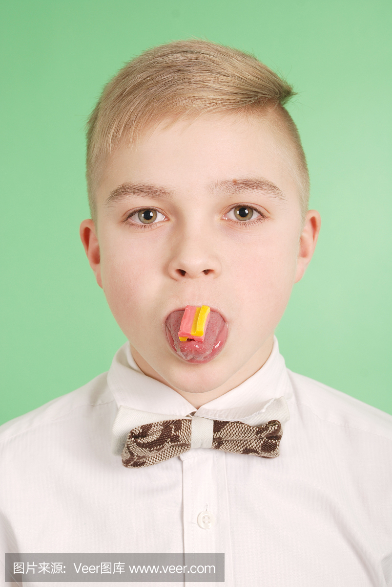 年轻的男孩把口香糖放在他的舌头上