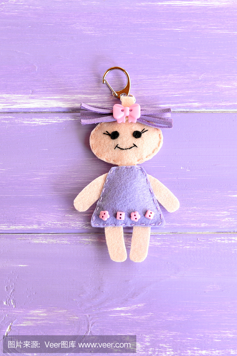 孤立在紫色木制背景上的可爱的小娃娃