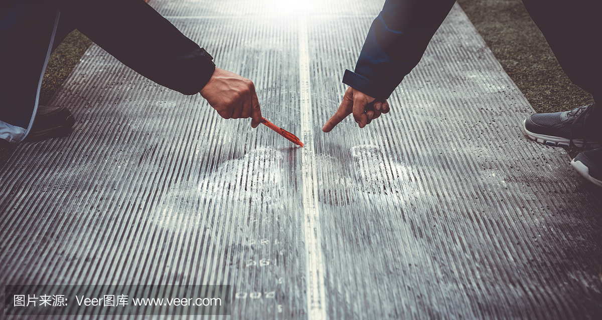 由两名裁判测量跳远。体育一天比赛活动的背景