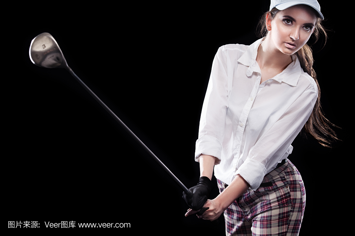 女子高尔夫球手击中孤立在黑色背景上的球。复