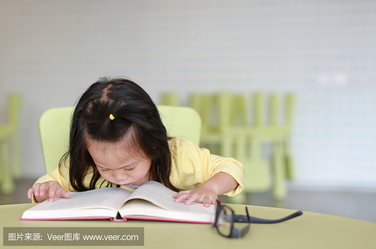 聪明的小女孩看书在房间们的孩子女生小组合里打算。图片