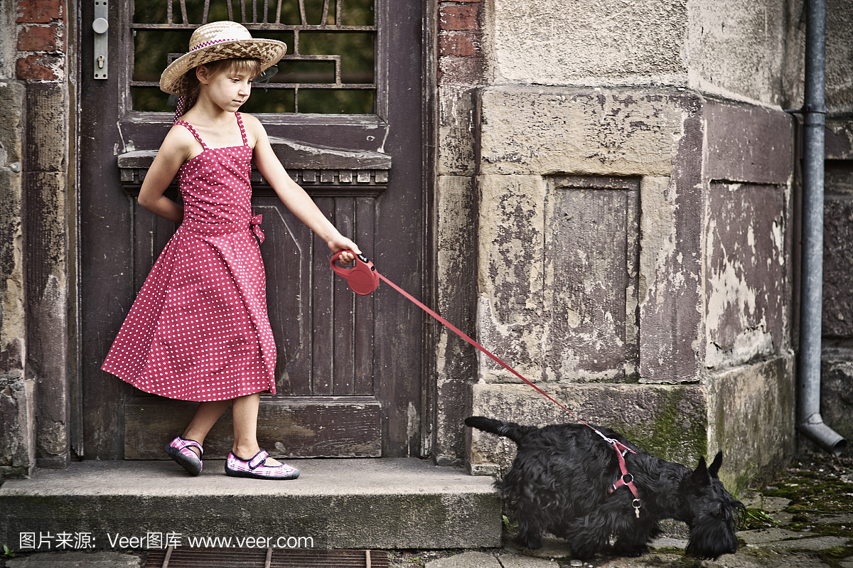 小女孩和狗在老房子前面。