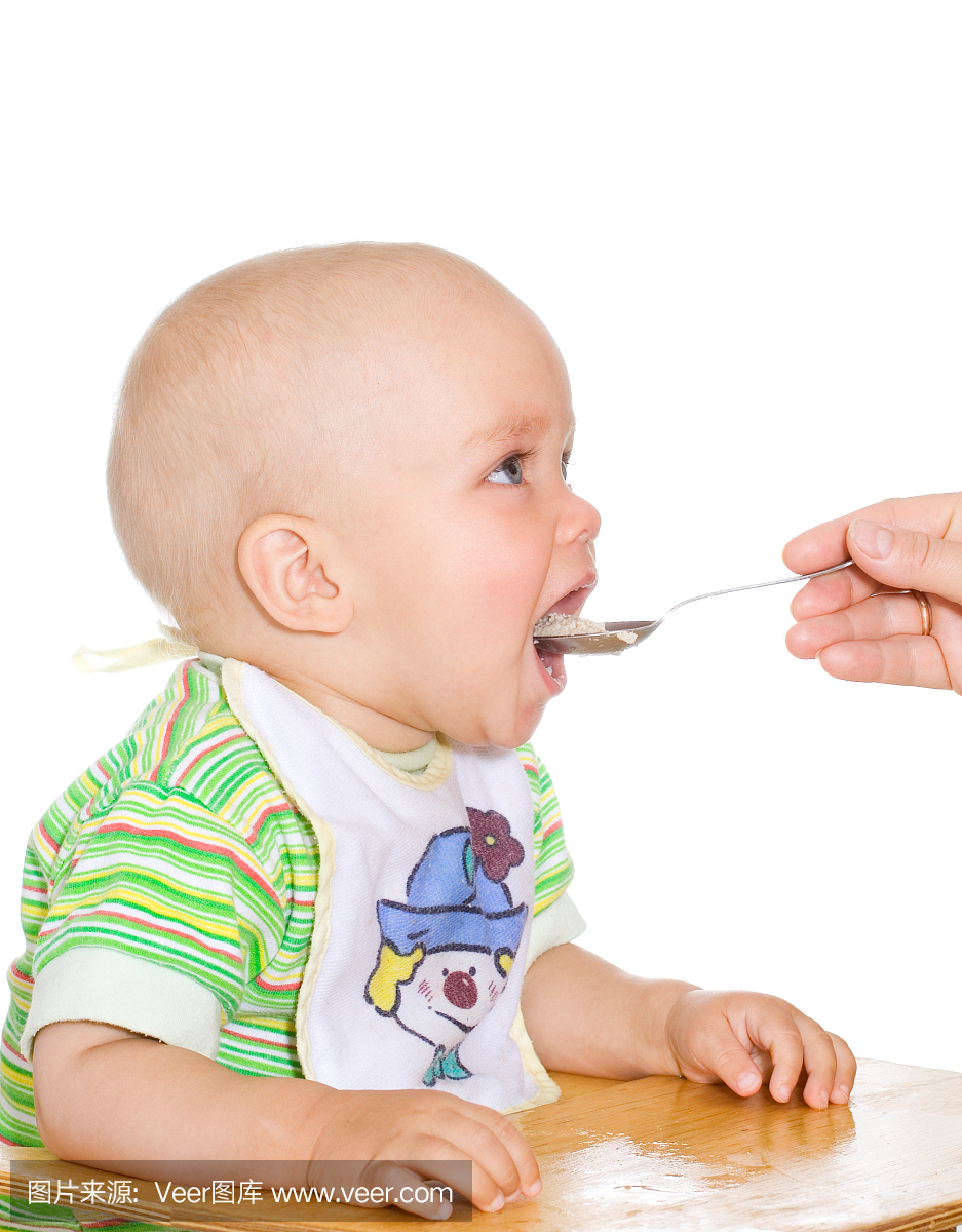 可爱的宝宝吃与勺子在白色背景上