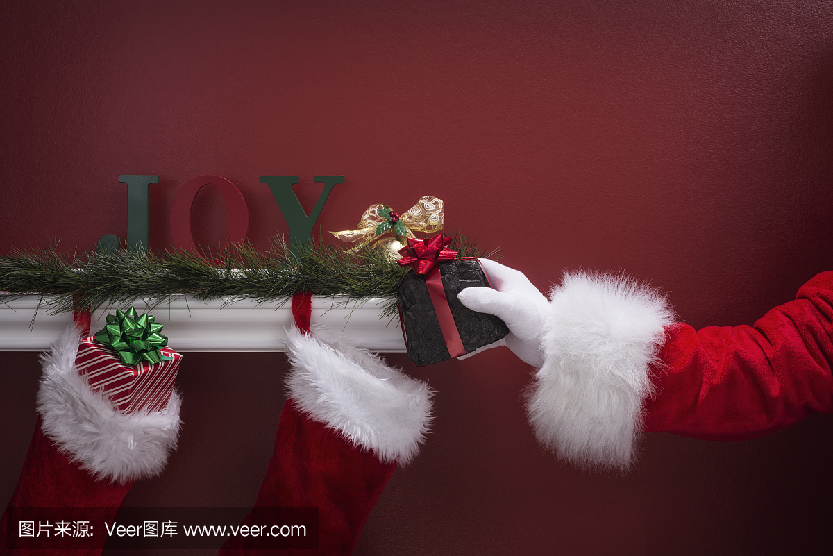 圣诞老人的手将煤放入圣诞袜