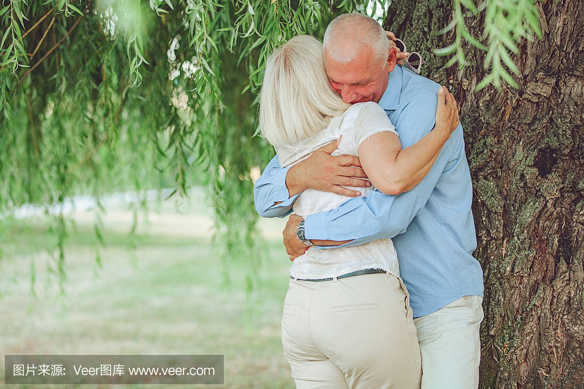 一个幸福的高级情侣拥抱和亲吻在树梢的肖像