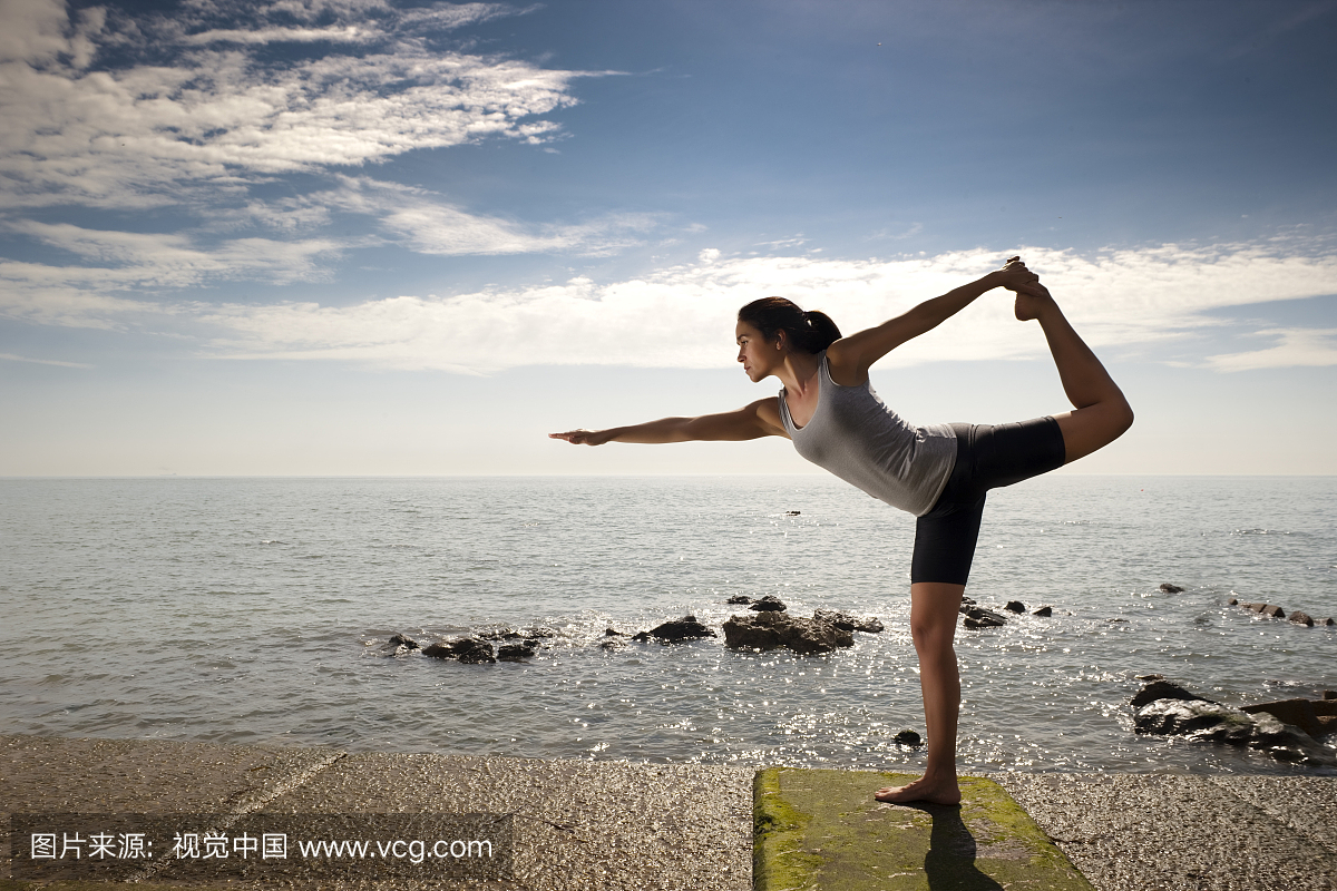 Woman practicing yoga by the ocean