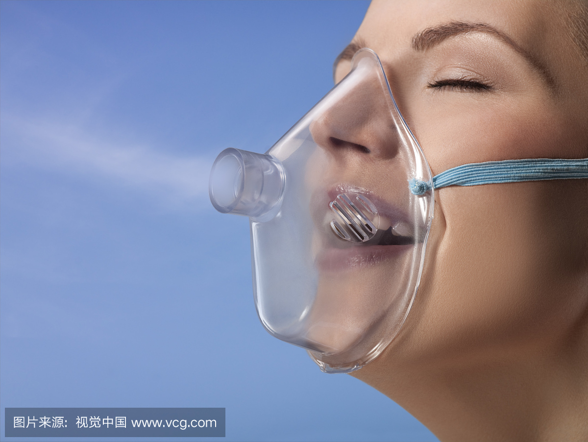 Young woman wearing oxygen mask, studio sh
