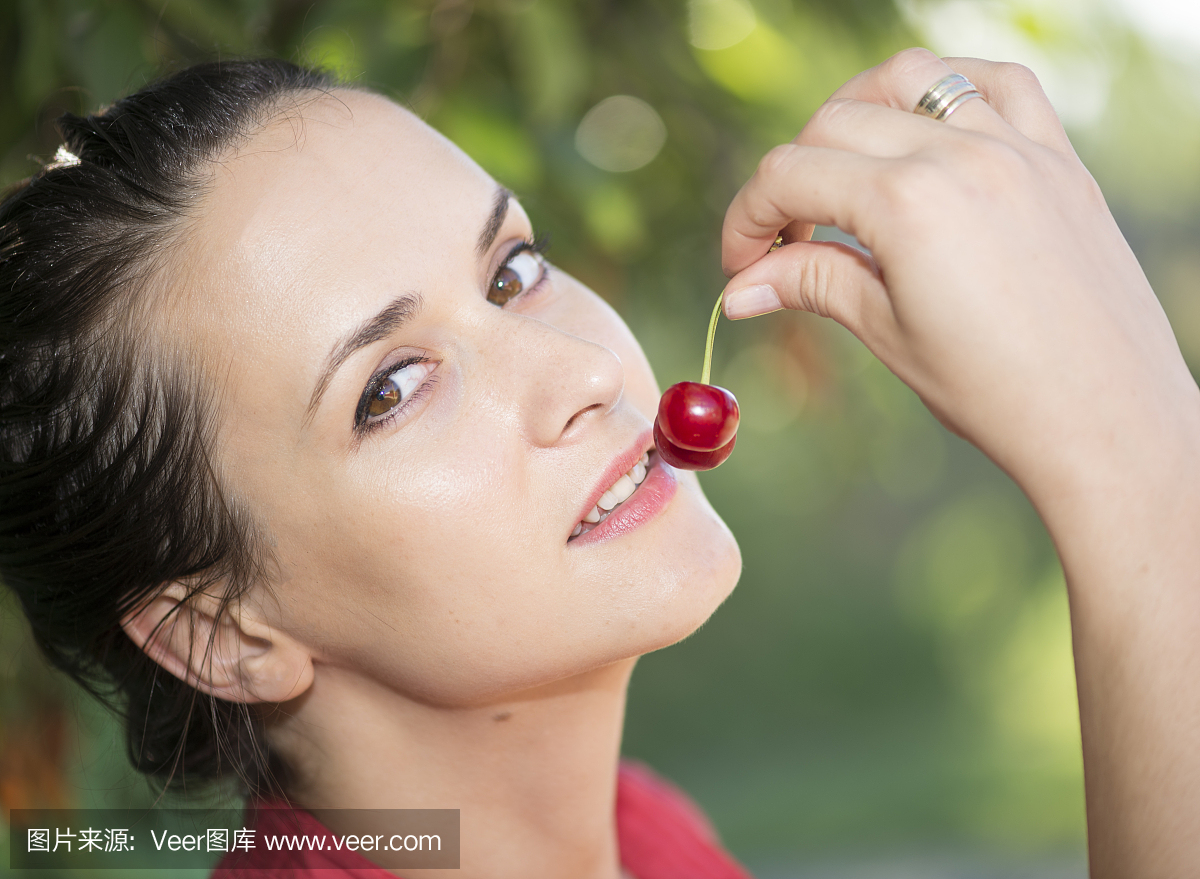 年轻女孩在户外吃樱桃