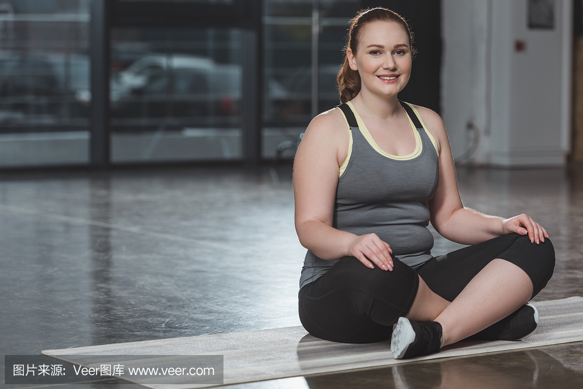 在凝思期间在健身房的肥胖微笑的女孩