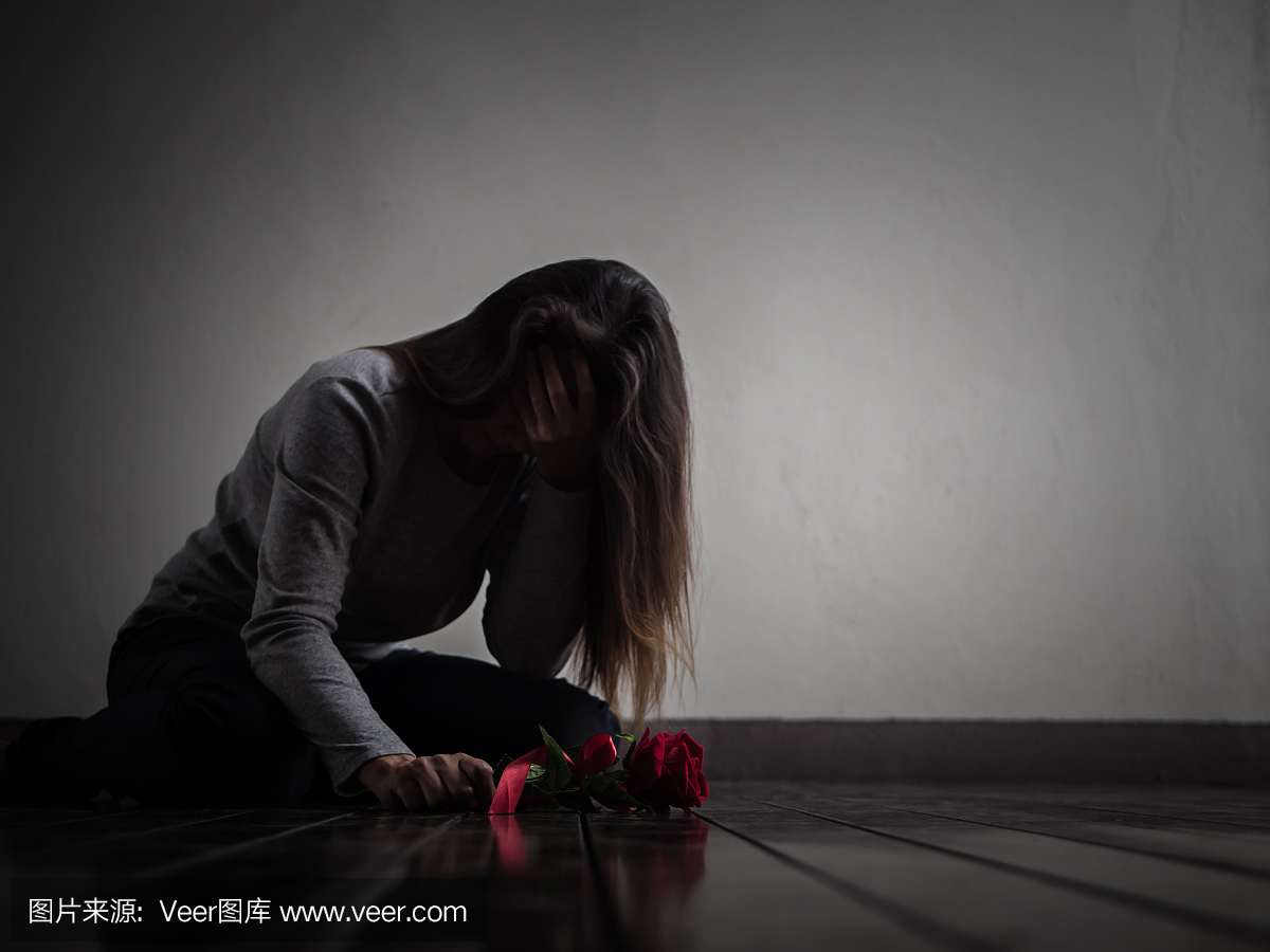 伤心的女人坐在她手里哭泣着红玫瑰。孤独,爱