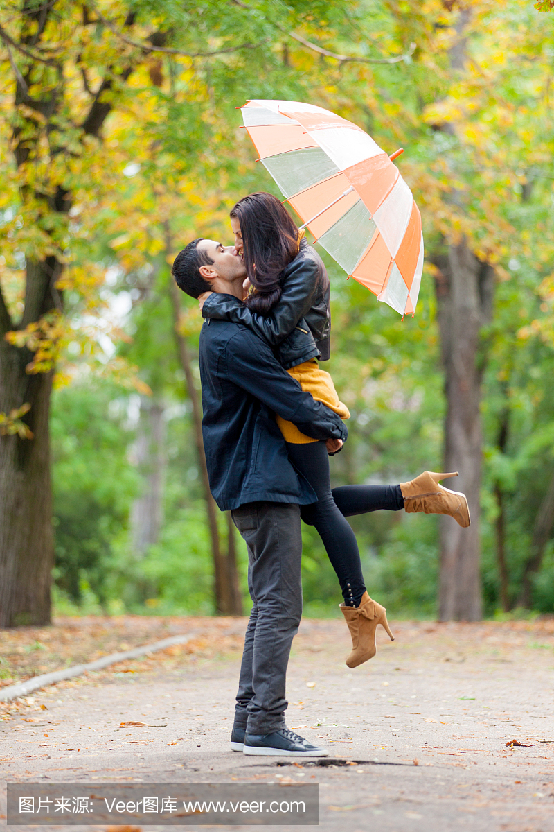 可爱的情侣拥抱和亲吻的照片在美丽的秋天公园