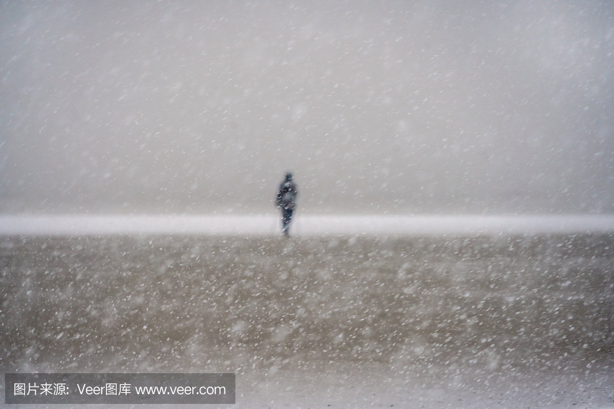 在一场暴风雪期间空的北海海滩上的女人