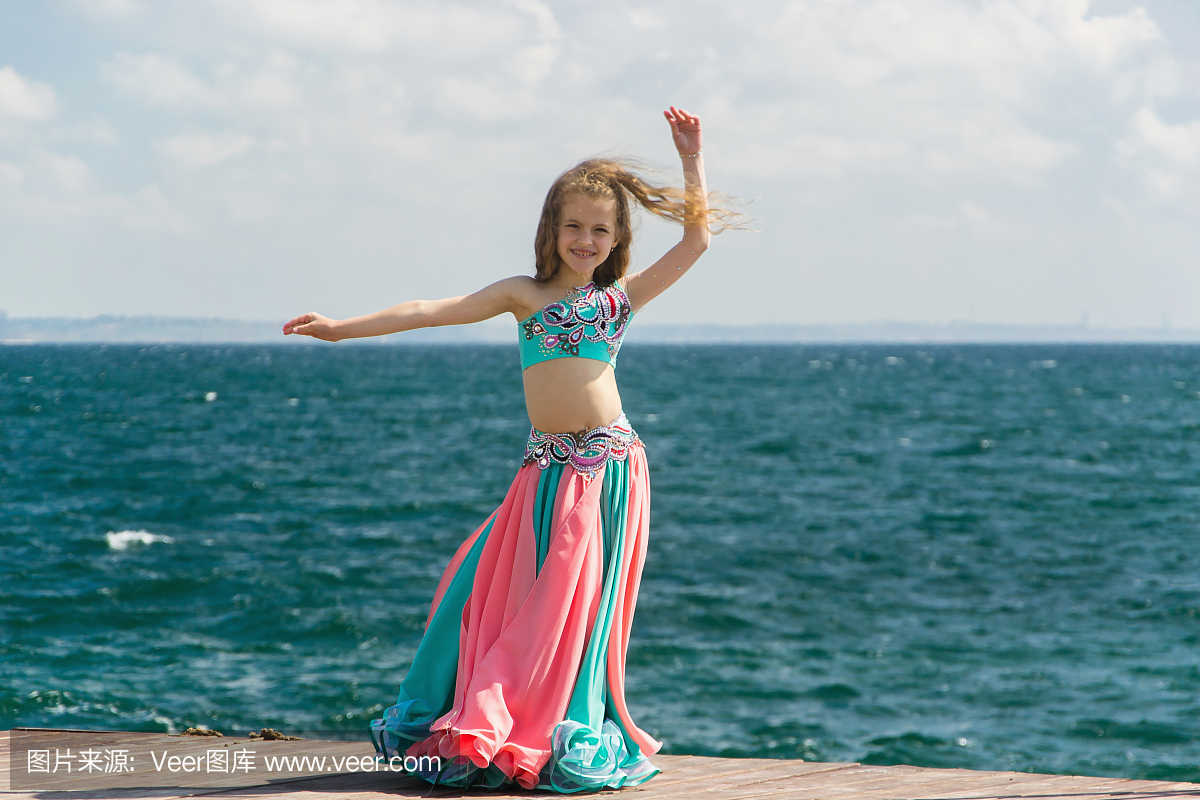 年轻女子肚皮舞者在海上表演