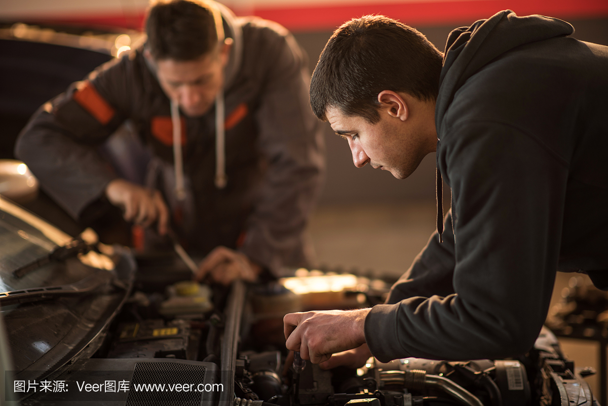 汽车维修店修理汽车的年轻机修。