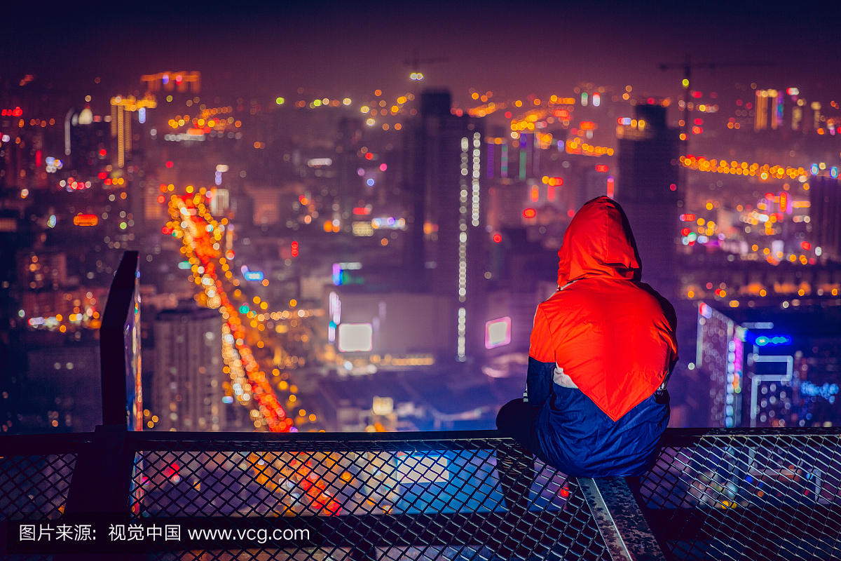站在屋顶俯瞰城市夜景的人