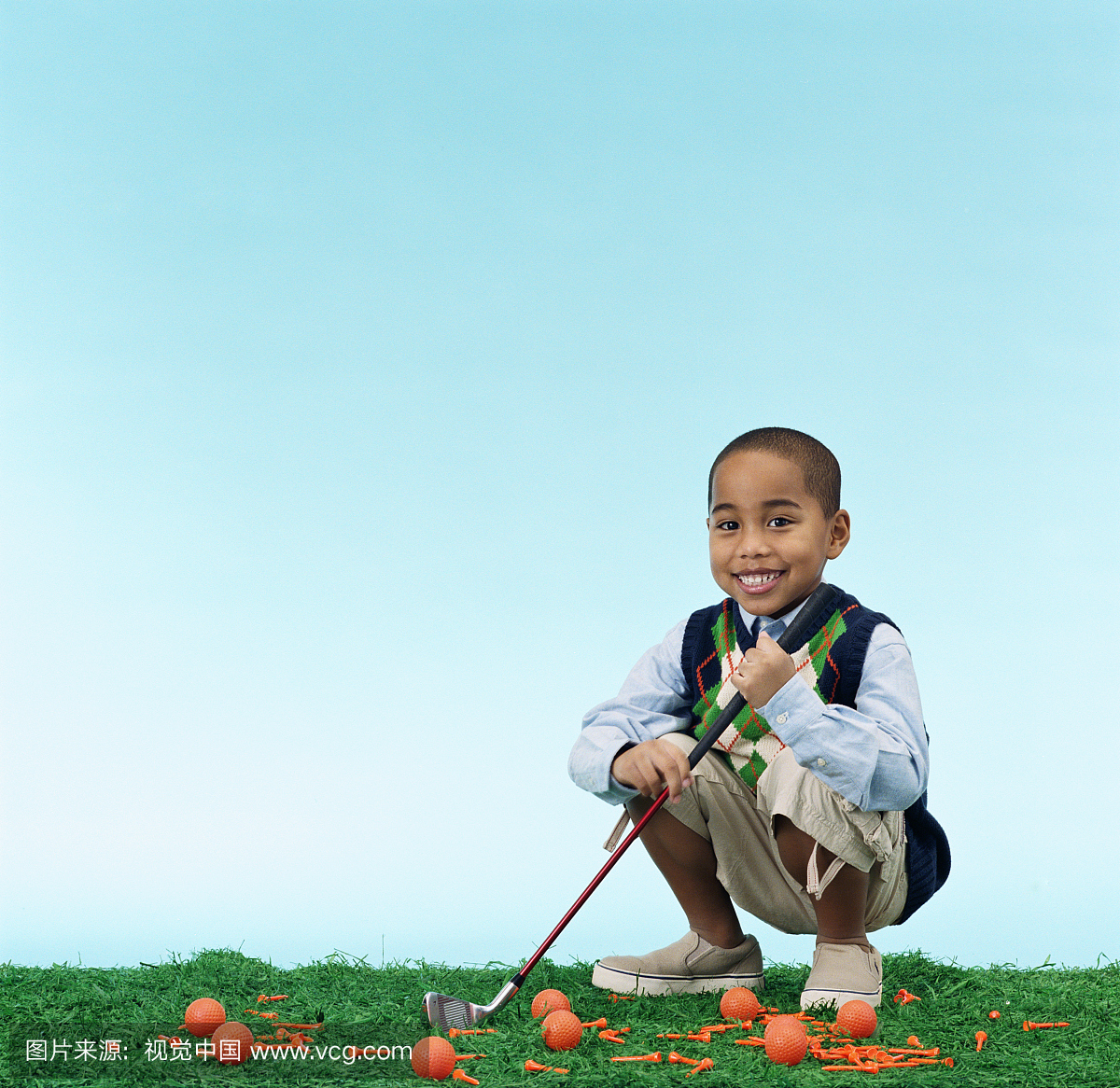 男孩(5-7)拿着高尔夫球杆,蹲着球和三通,肖像