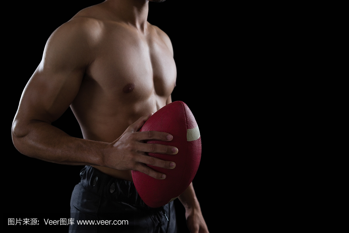 肌肉的美式足球球员在他的手中持有一个足球