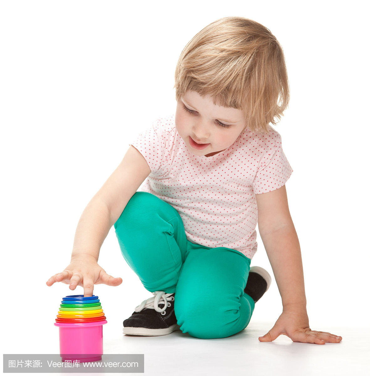 可玩的小女孩玩玩具坐在地板上
