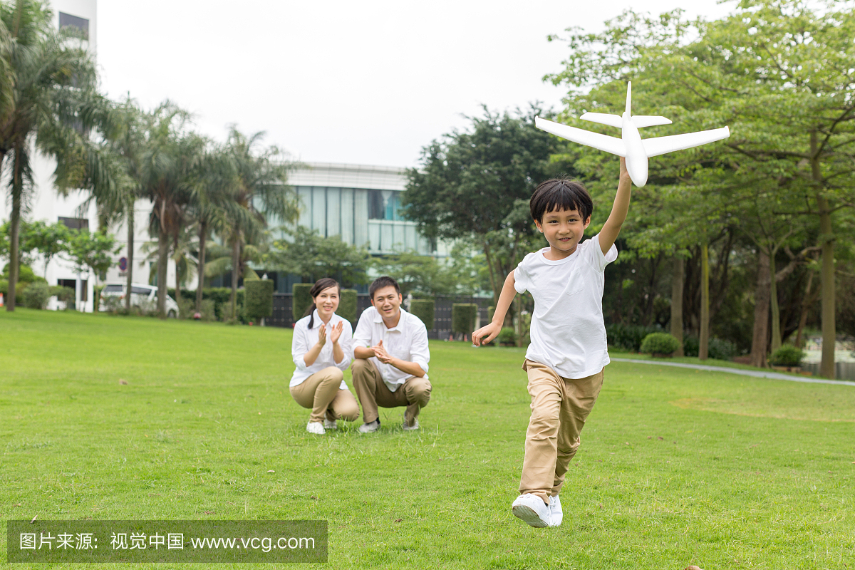 快乐的一家人在公园玩飞机模型