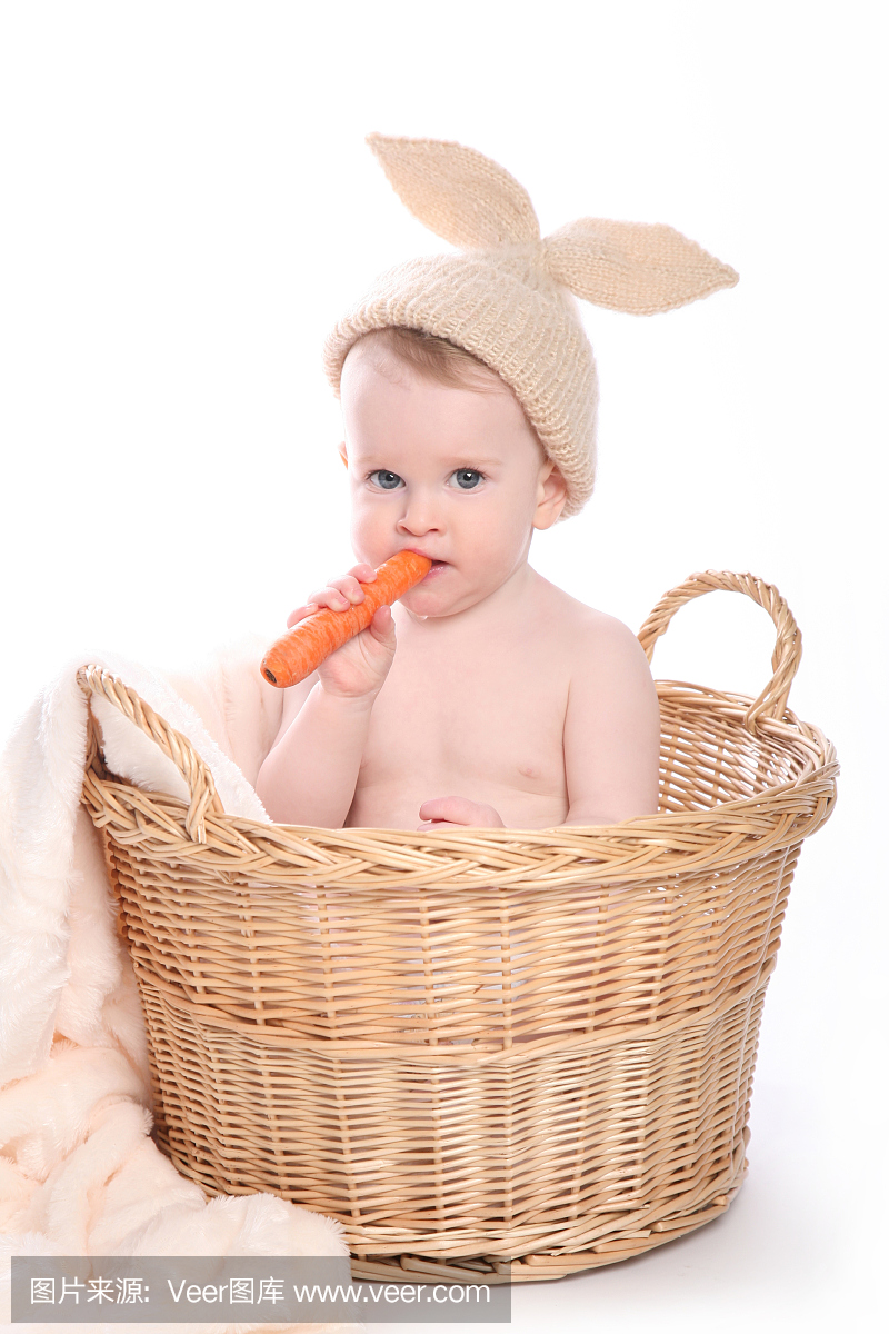 可爱的兔子男孩坐在篮子里吃胡萝卜