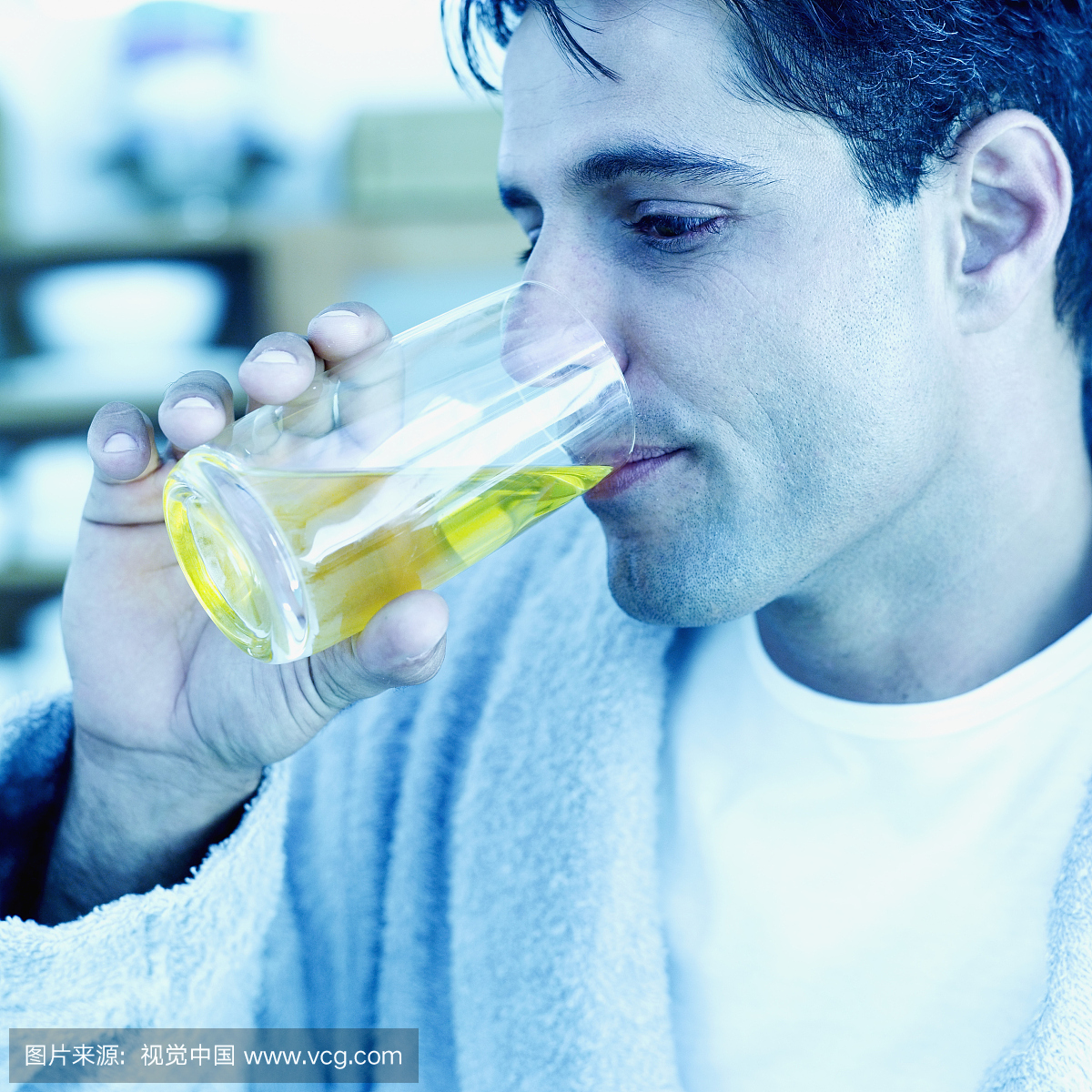 年轻人从玻璃杯喝果汁