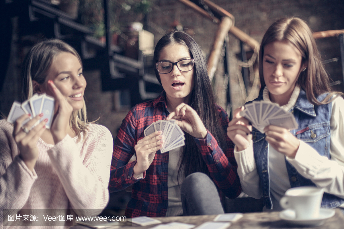 三个女孩在咖啡馆里玩游戏卡。