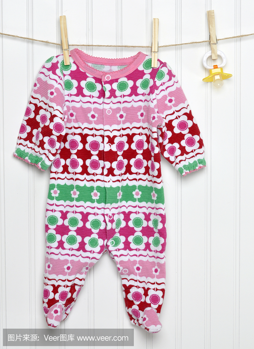 粉红色的婴儿睡眠者,安抚奶嘴放在晒衣绳上。