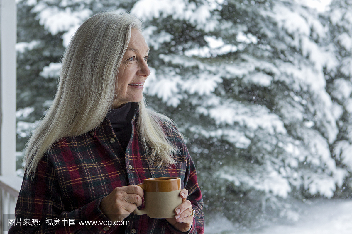 在白雪皑皑的天井喝咖啡的老白种人女人