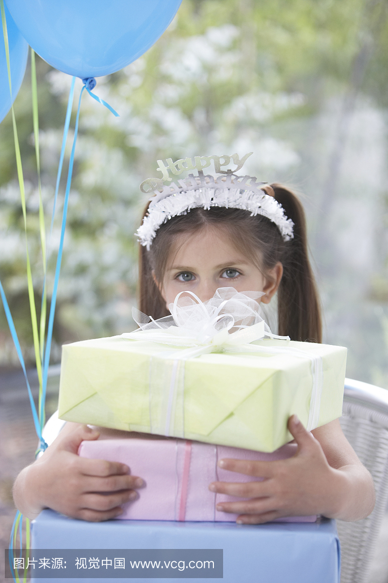 女孩(6-8)戴着生日快乐冠,拿着礼物,肖像