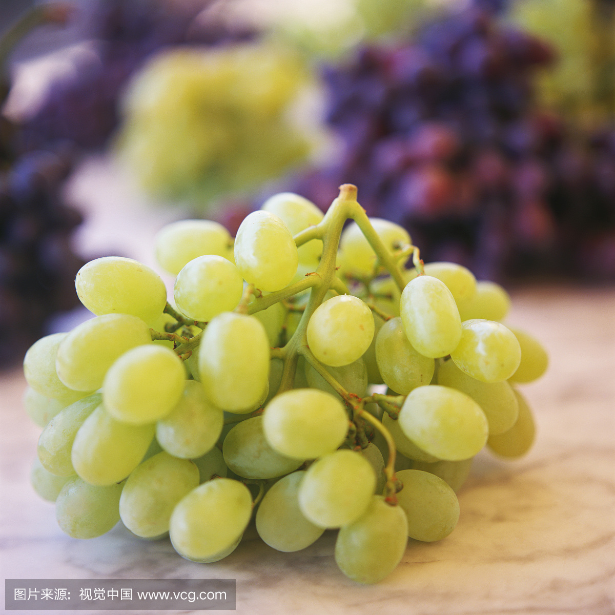 Green grapes on marble platter in front of mixed