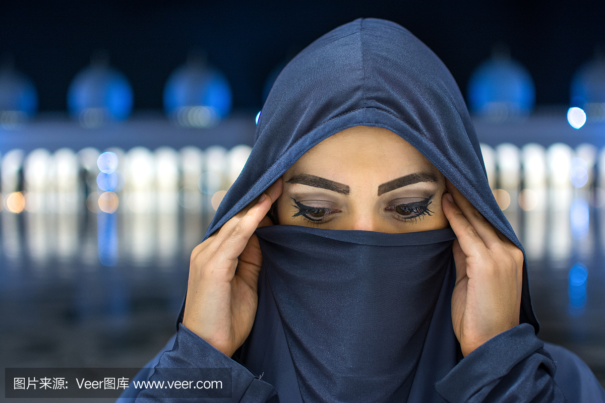 关闭美丽的年轻穆斯林妇女在晚上戴头巾俯视清