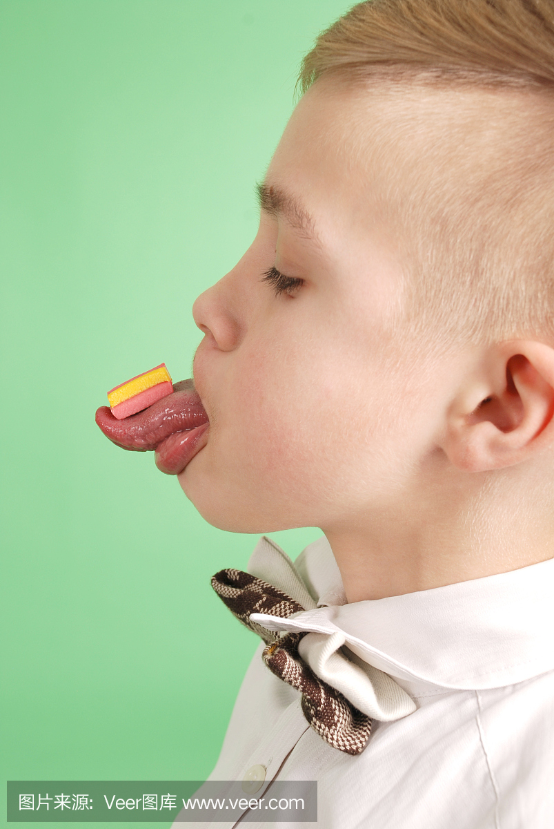 年轻的男孩把口香糖放在他的舌头上