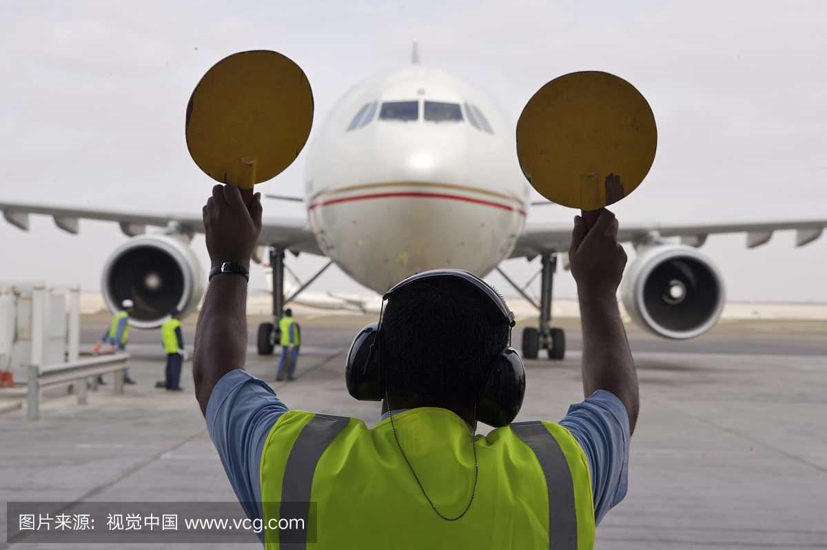 一架飞机由阿布扎比机场的地勤人员指挥到其架