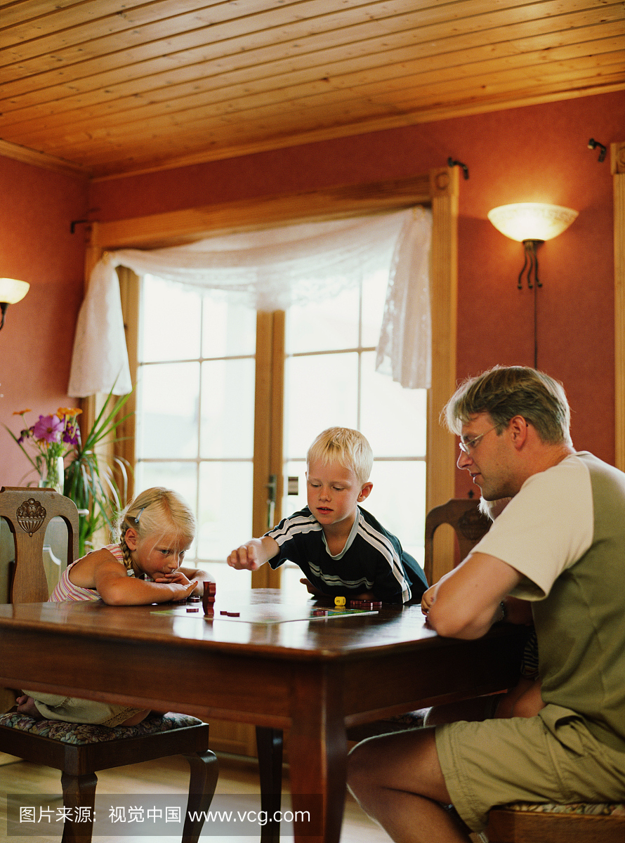 父亲与孩子玩棋盘游戏(6-8)在桌上