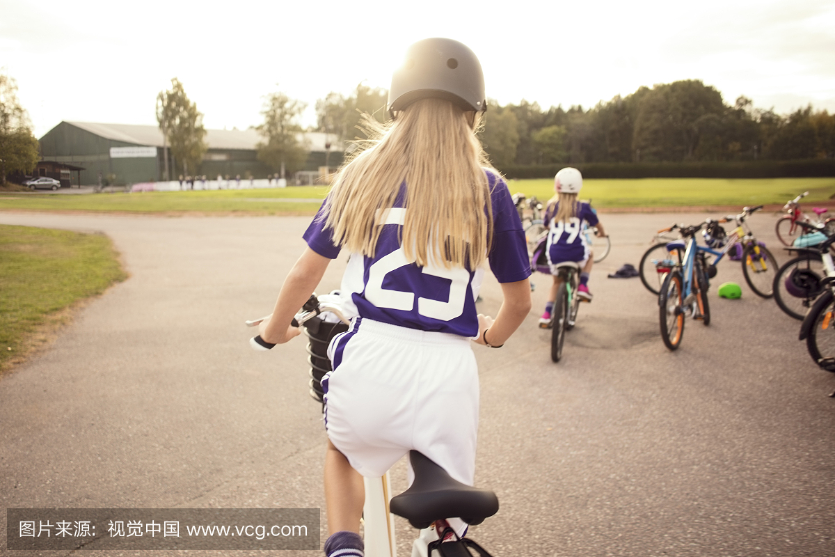循环在小径的女孩背面图由足球场反对天空